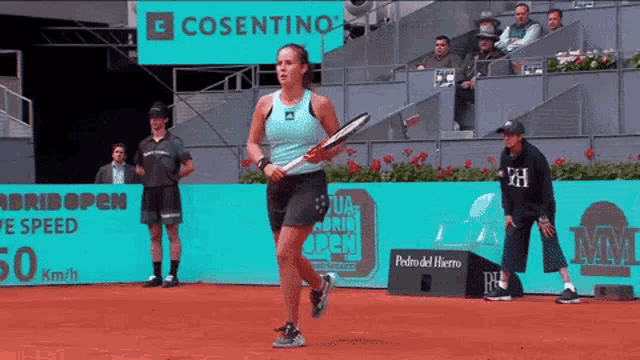 a woman is holding a tennis racquet on a court in front of a sign that says cosentino