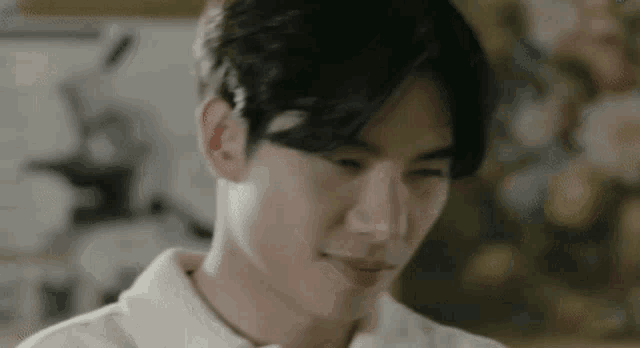 a young man in a white shirt is making a funny face while sitting in front of a painting .