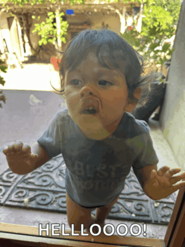 a baby standing in front of a glass door with the words hellooo on it