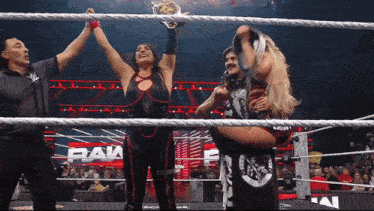 a woman in a wrestling ring holds up a trophy in front of a crowd that says raw