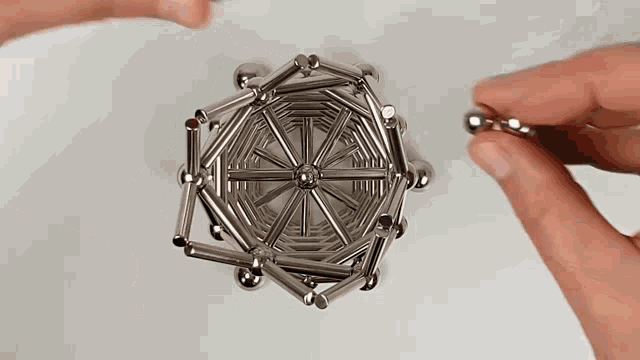 a person is holding a stack of magnetic sticks and balls in their hands .