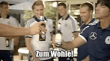 a group of men are drinking beer and one of them is holding a bottle that says zum wohlei on it