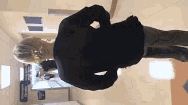 a woman is walking down a hallway in a hospital with her hands on her hips .