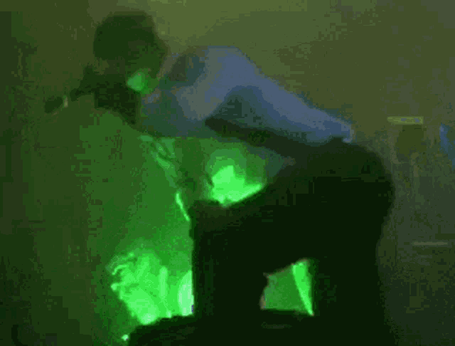 a man is singing into a microphone while sitting on a stage in front of a green light .