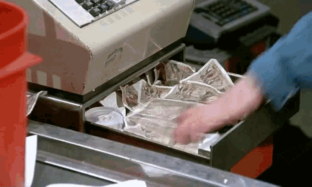 a person is taking money out of a cash register that has a calculator on it