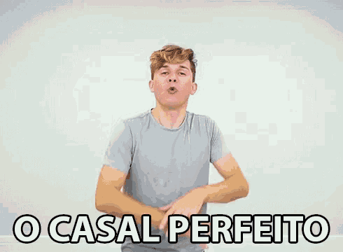 a man in a gray shirt is standing in front of a white wall and says o casal perfeito
