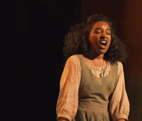a woman in a green dress is screaming into the air