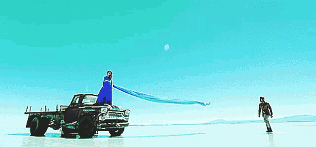 a woman in a blue dress is standing on the back of a truck that says ' ford ' on it