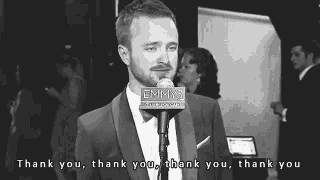a man in a suit is standing in front of a microphone that says emmys on it .