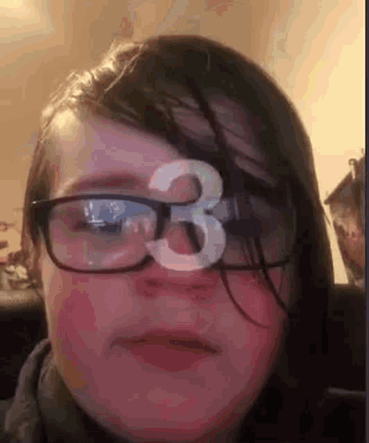 a young girl wearing glasses with a number three on her forehead .