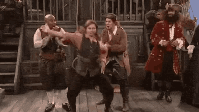 a group of people dressed in pirate costumes are dancing on a stage .