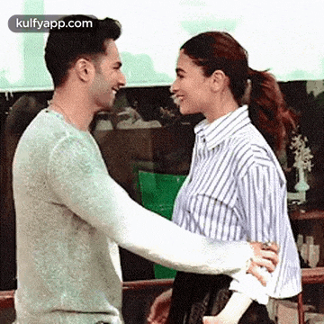 a man and a woman are hugging each other and smiling at each other .
