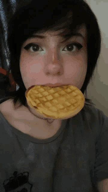 a woman with a waffle in her mouth and a crown on her shirt