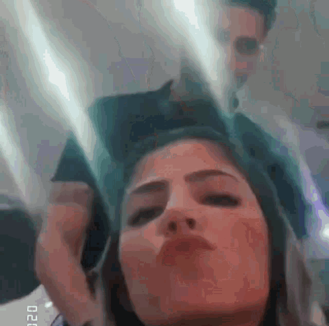 a close up of a woman making a funny face while a man holds her head .