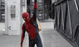 a man in a spiderman costume is standing in a hallway with his arm up .