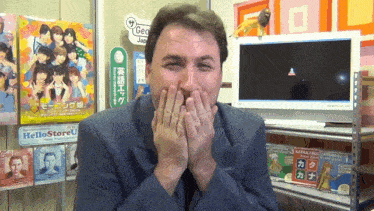 a man covering his mouth with his hands in front of a sign that says " hellostoreu "