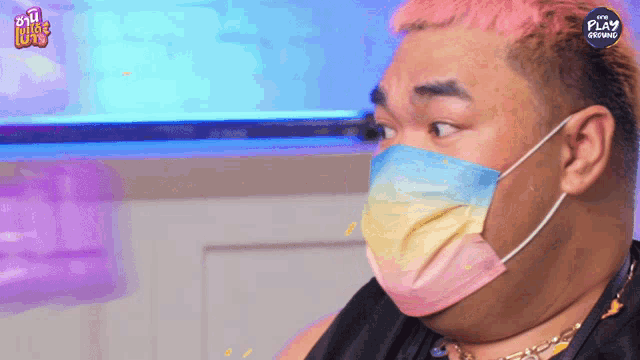 a man wearing a rainbow colored face mask with the play logo on the bottom right