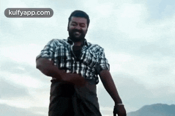 a man in a plaid shirt is standing on top of a hill .