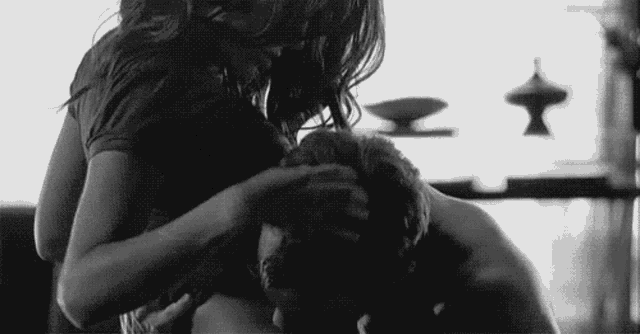 a black and white photo of a woman touching a man 's face .