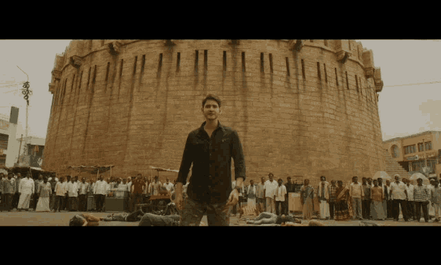 a man stands in front of a large brick building