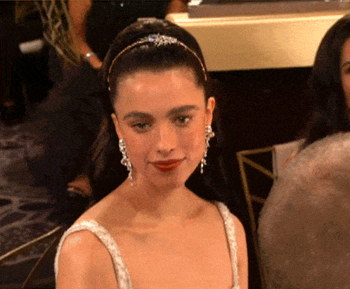 a woman wearing a headband and earrings is sitting in a crowd