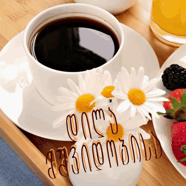 a cup of coffee on a saucer next to flowers and strawberries