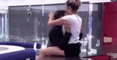 a woman is sitting on a man 's lap on a counter .