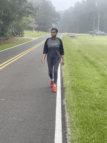 a woman walking down a road wearing red shoes and a black shirt
