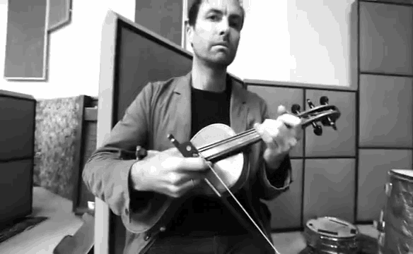 a man is playing a violin in a room in a black and white photo .