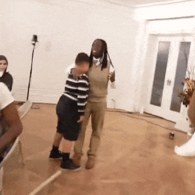 a man with dreadlocks is hugging a boy in a living room