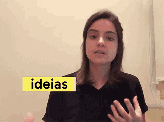 a woman in a black shirt stands in front of a yellow sign that says " ideias "