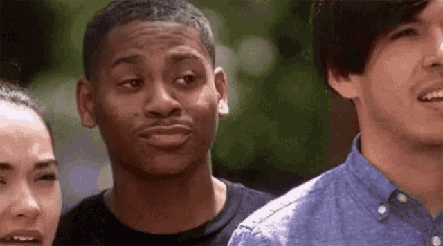 a man is making a funny face while standing next to two other men .