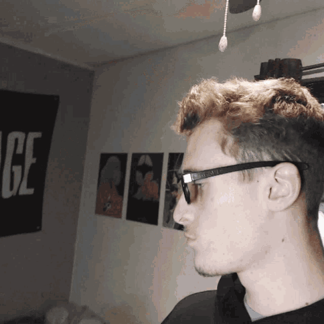 a young man wearing glasses stands in front of a sign that says ge
