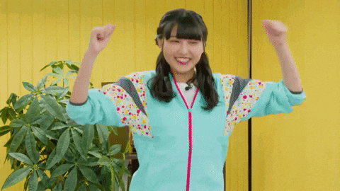 a girl in a blue shirt is dancing in front of a yellow wall .