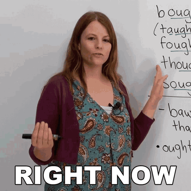 a woman is standing in front of a white board with the words right now written on it