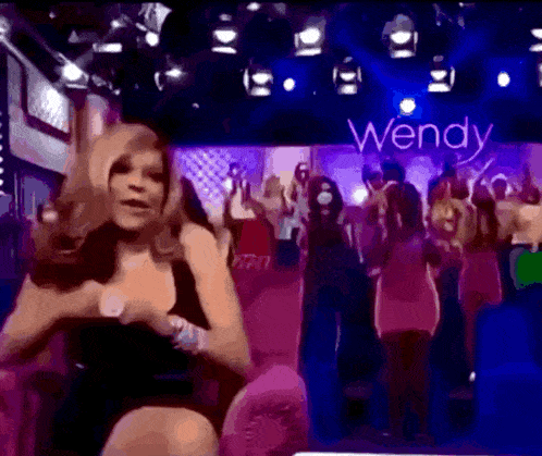 a woman is dancing in front of a sign that says wendy on it
