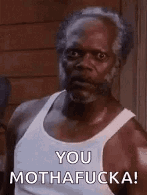 a man with a beard is wearing a white tank top and making a funny face .