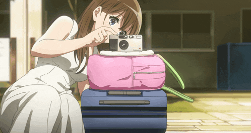 a girl taking a picture of a pink bag with a camera on top of it