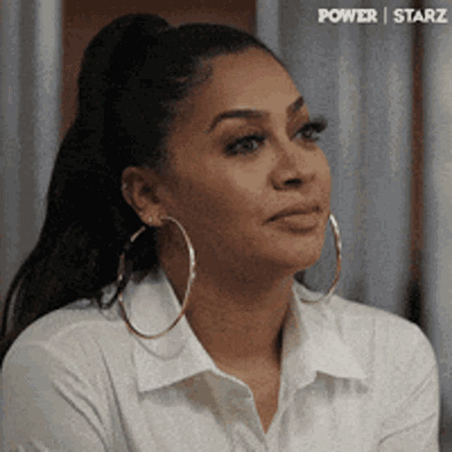 a woman wearing hoop earrings and a ponytail looks to the side
