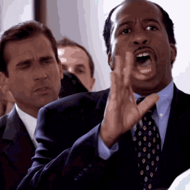a man in a suit and tie is screaming in a crowd