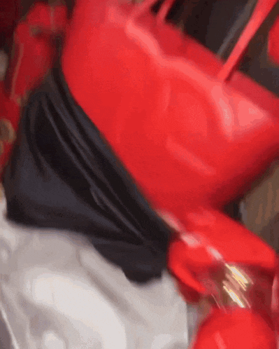 a close up of a red purse with a black belt around it