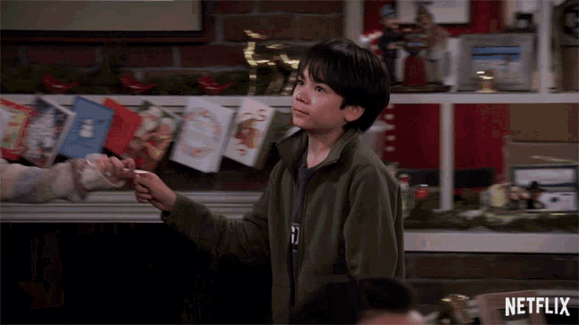 a boy in a green jacket is standing in front of a shelf with a netflix logo