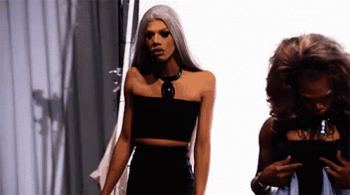 two women are standing next to each other in front of a white curtain .