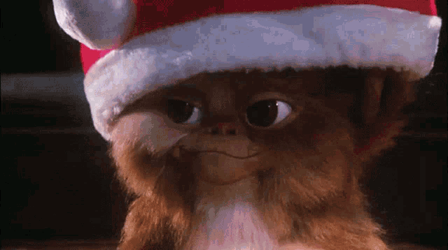 a gremlin wearing a santa hat is smiling