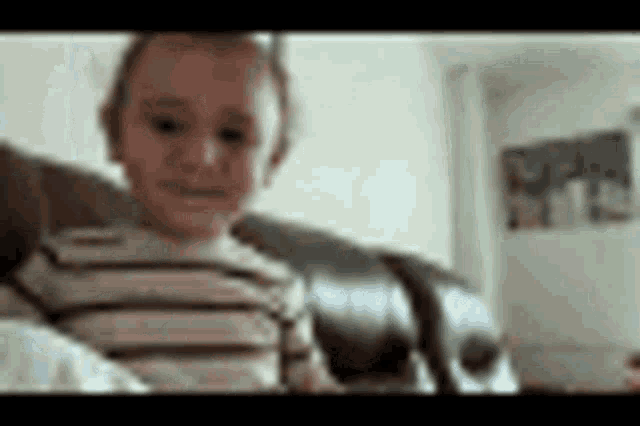 a young boy is sitting on a couch in a living room .