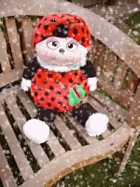 a ladybug stuffed animal sitting on a wooden bench