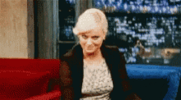a woman is sitting on a red couch and making a funny face .