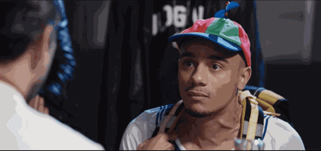 a man wearing a colorful hat is looking at himself in the mirror
