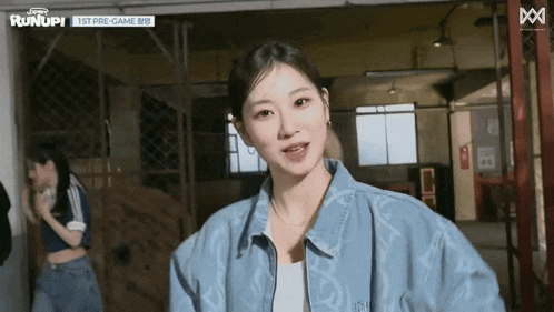a woman in a blue jacket is standing in a room with a sign that says runup on it