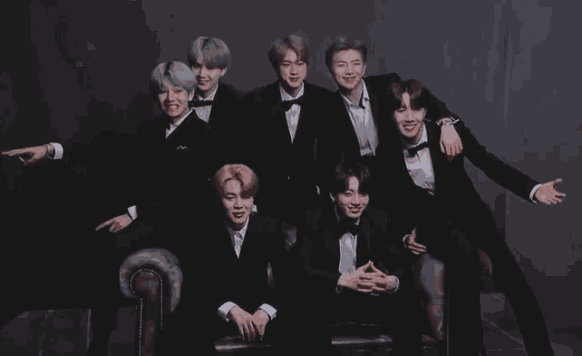 a group of young men wearing tuxedos pose for a picture